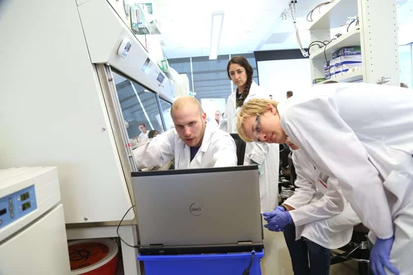 Daniel Gil, a graduate researcher in the Multiscale Imaging in Medicine Lab led by Melissa Skala, manipulates a microscope under the hood while the cellular image projects on a laptop. The Skala Lab led a multi-day research project with the campers looking at treatments for cancer cells.