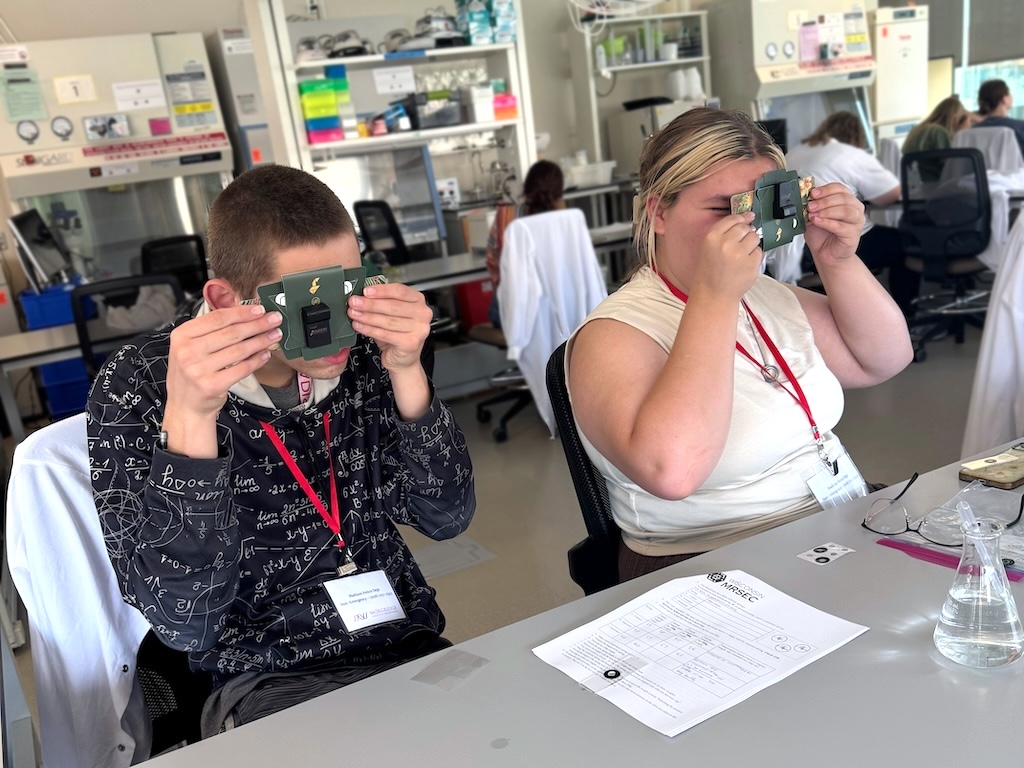 Summer campers unlock the mysteries of microscopes as they construct their own foldscopes out of paper and optical lenses to observe single cells.