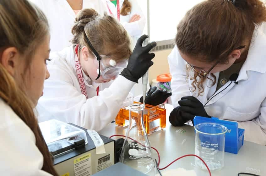 A camper loads plant DNA into a gel electrophoresis device that will analyze the samples, as part of an activity on epigenetics. Activity presented by the Xuehua Zhong Lab.